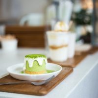 Close-up of green tea cake on white plate with cream cheese and